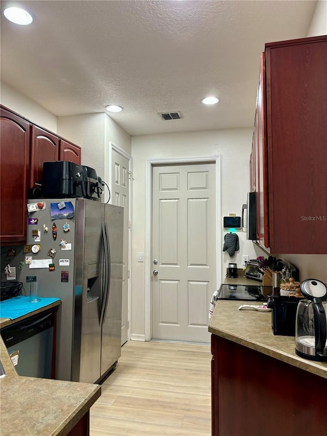 kitchen featuring a textured ceiling, stainless steel appliances, and light hardwood / wood-style flooring