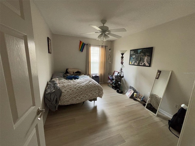 bedroom with a textured ceiling, light hardwood / wood-style flooring, and ceiling fan