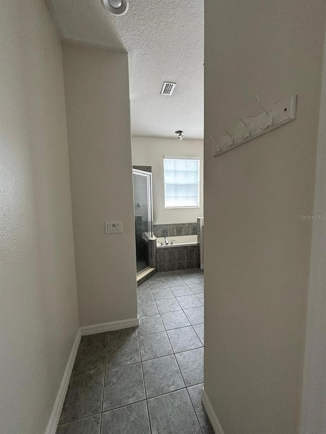 corridor featuring a textured ceiling and tile patterned floors