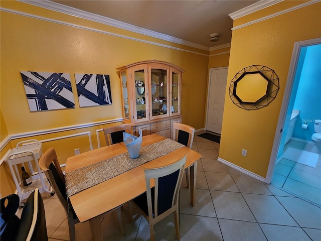 tiled dining space with crown molding and baseboards