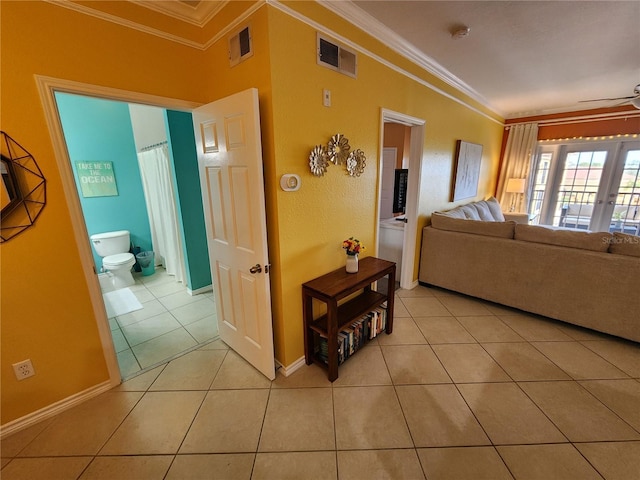 hall with light tile patterned flooring, visible vents, and crown molding