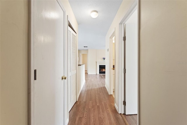 hall with a textured ceiling and light wood-type flooring