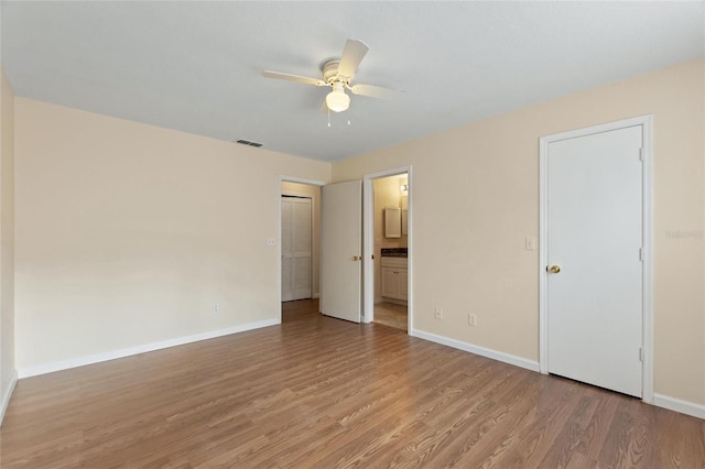 unfurnished bedroom featuring ensuite bath, ceiling fan, and light hardwood / wood-style flooring