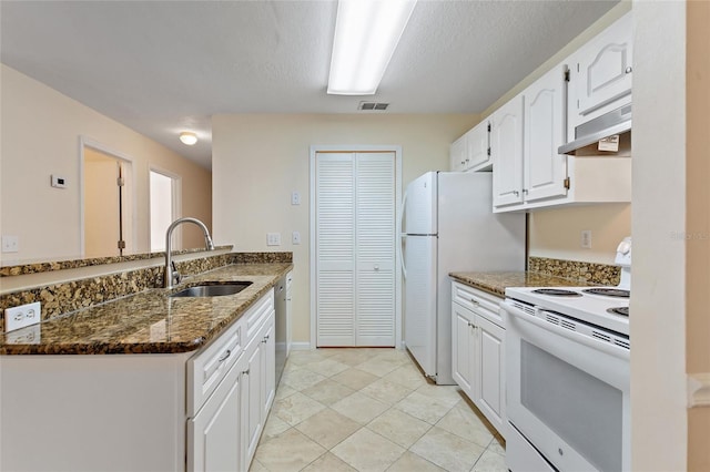 kitchen with kitchen peninsula, white appliances, sink, dark stone countertops, and white cabinetry