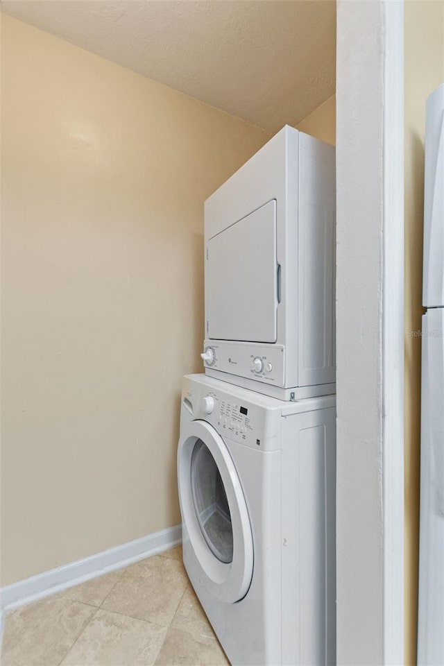 washroom featuring stacked washer / dryer and light tile patterned flooring