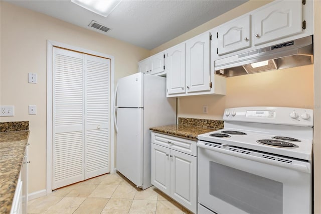 kitchen with white cabinetry, light tile patterned flooring, dark stone counters, and white appliances