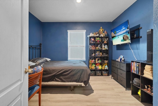 bedroom with a textured ceiling and light hardwood / wood-style flooring