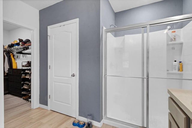 bathroom with a shower with shower door, wood-type flooring, and vanity