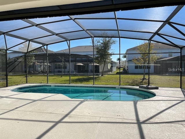 view of pool featuring glass enclosure, a yard, and a patio