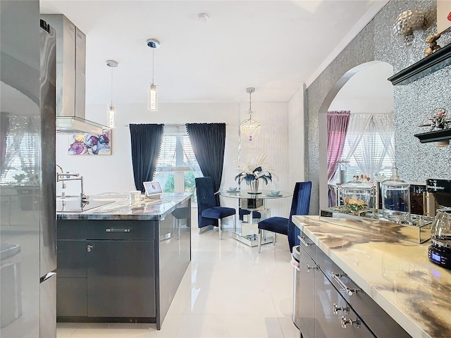 kitchen featuring backsplash, wall chimney exhaust hood, light tile patterned floors, decorative light fixtures, and stovetop