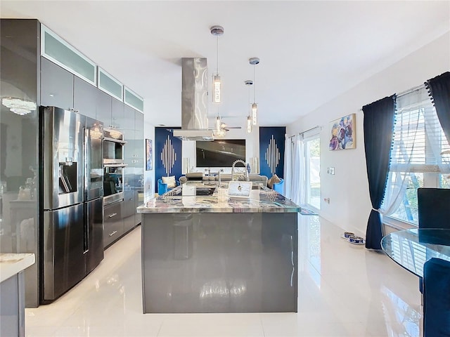 kitchen featuring island exhaust hood, stainless steel refrigerator with ice dispenser, light stone countertops, decorative light fixtures, and a center island with sink