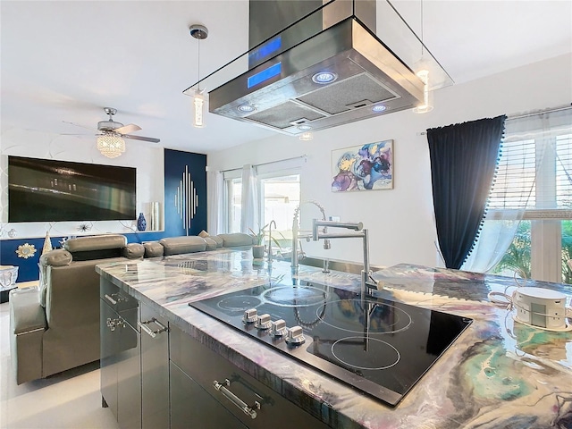 kitchen featuring black electric stovetop, ceiling fan, island range hood, and a healthy amount of sunlight