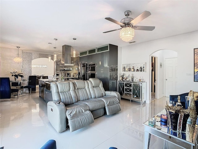 tiled living room with ceiling fan and sink