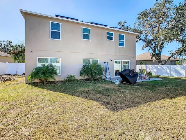 back of house featuring a lawn and a patio