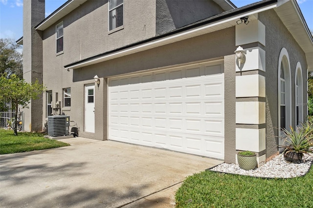 view of side of home featuring driveway, central AC unit, and stucco siding