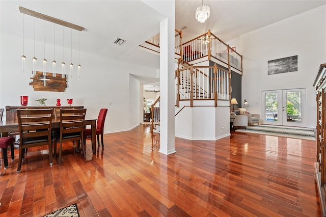 dining area featuring visible vents, baseboards, wood-type flooring, an inviting chandelier, and stairs