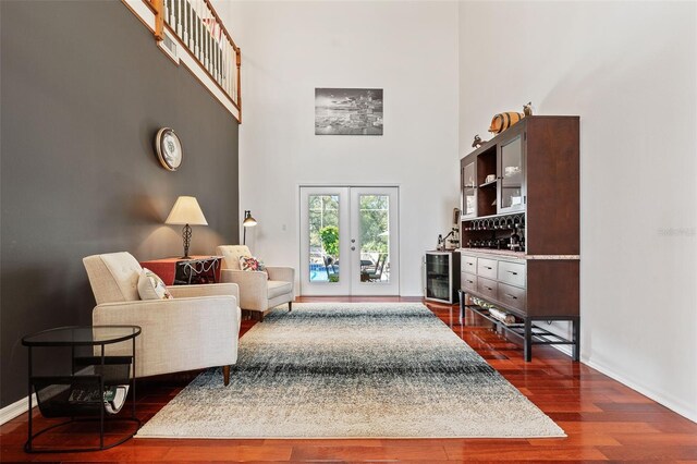 sitting room with dark wood-style floors, french doors, a towering ceiling, and baseboards