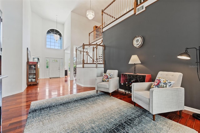 interior space with a high ceiling, wood finished floors, baseboards, stairs, and an inviting chandelier