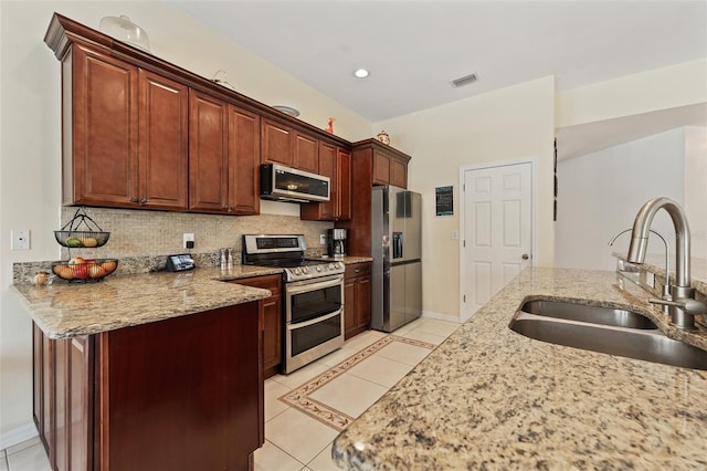 kitchen featuring backsplash, appliances with stainless steel finishes, light tile patterned flooring, a sink, and a peninsula