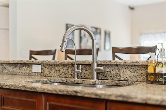 interior details featuring light stone counters and a sink