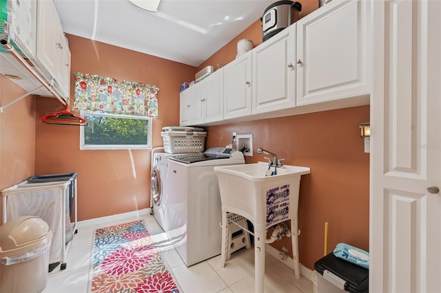 clothes washing area featuring baseboards, light tile patterned flooring, cabinet space, and washer and dryer