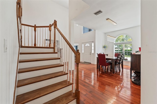 interior space featuring visible vents, a towering ceiling, hardwood / wood-style floors, and stairs