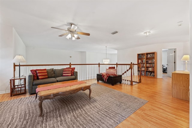 living area with light wood-style floors, ceiling fan, visible vents, and baseboards