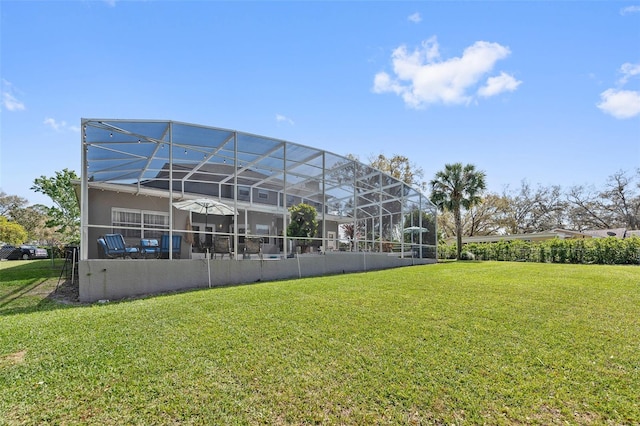 rear view of property featuring glass enclosure, a lawn, and stucco siding