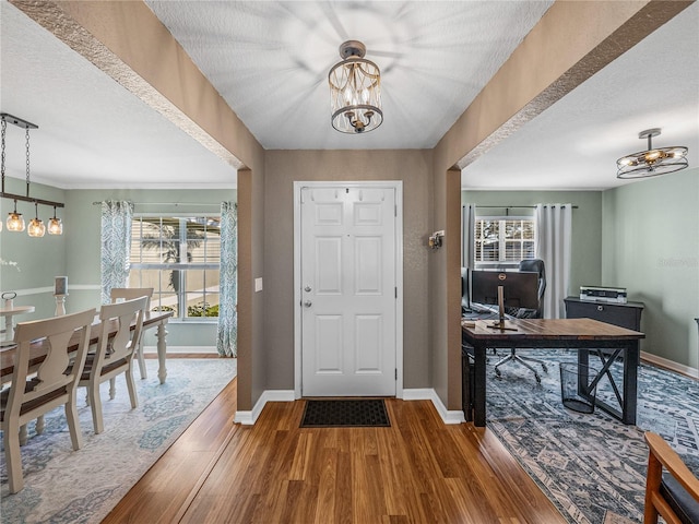 entryway with a textured ceiling, plenty of natural light, a notable chandelier, and hardwood / wood-style flooring