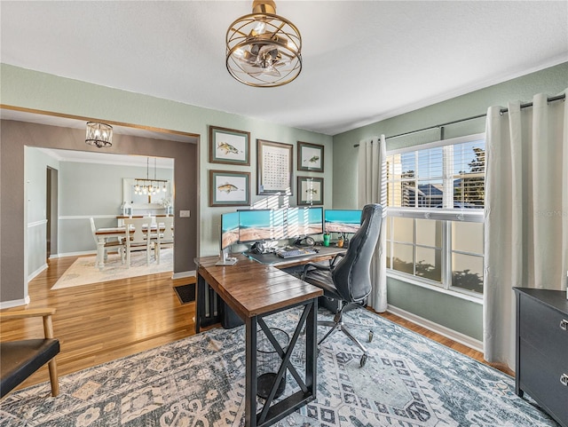 office area with wood-type flooring and an inviting chandelier