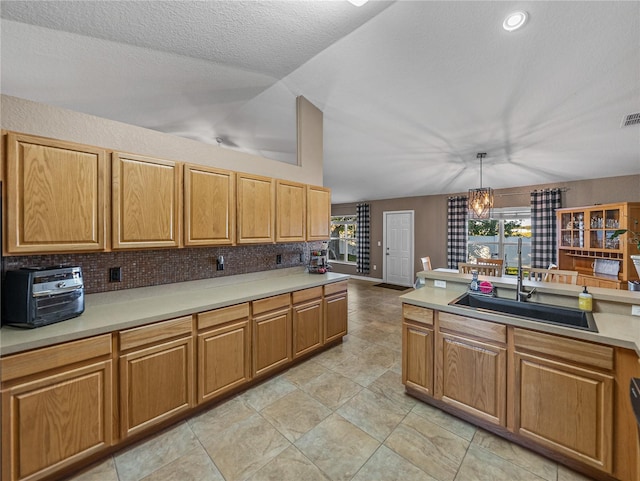 kitchen featuring sink, decorative light fixtures, tasteful backsplash, a notable chandelier, and a healthy amount of sunlight