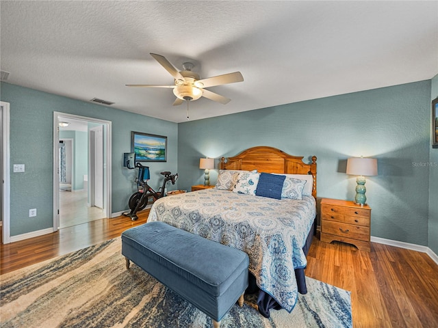 bedroom featuring hardwood / wood-style floors, ceiling fan, a textured ceiling, and connected bathroom