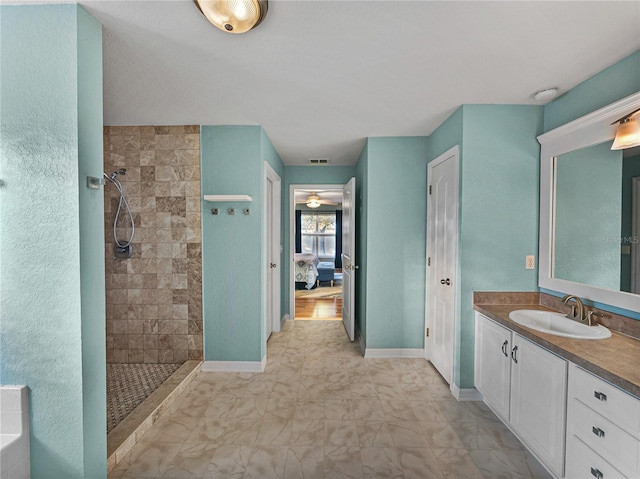 bathroom with tiled shower, vanity, and ceiling fan