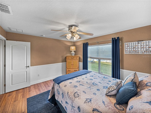 bedroom with ceiling fan, wood-type flooring, and a textured ceiling