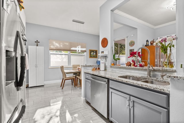 kitchen with light stone counters, stainless steel appliances, sink, gray cabinets, and plenty of natural light