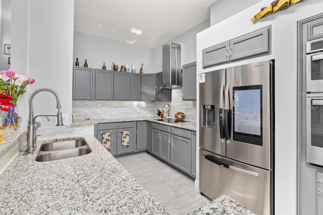 kitchen with light stone countertops, appliances with stainless steel finishes, gray cabinetry, wall chimney exhaust hood, and sink