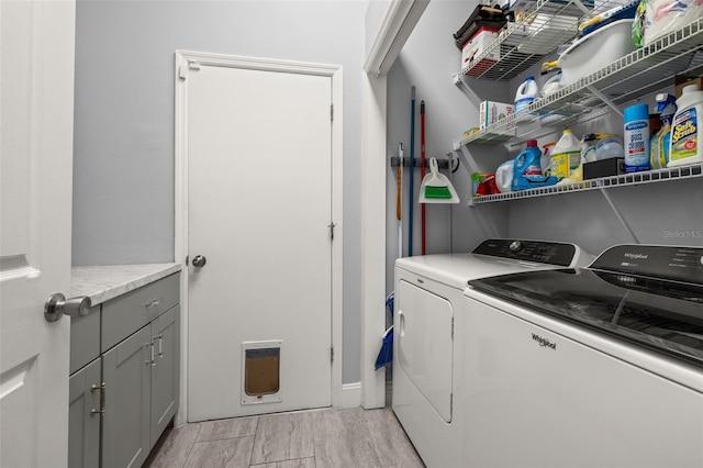 clothes washing area with separate washer and dryer, cabinets, and light hardwood / wood-style floors