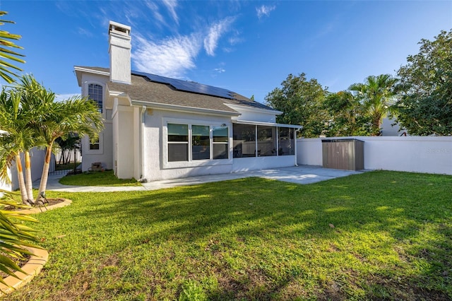 rear view of property with a lawn, a sunroom, and solar panels