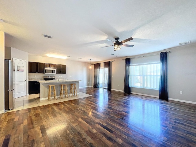 unfurnished living room with a textured ceiling, dark hardwood / wood-style flooring, and ceiling fan