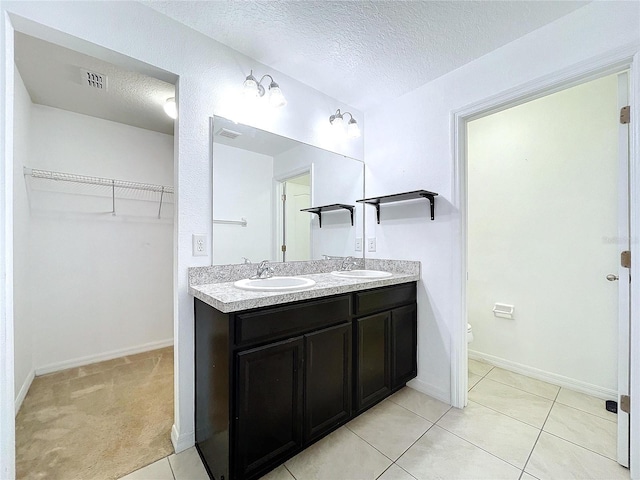 bathroom with tile patterned floors, vanity, toilet, and a textured ceiling