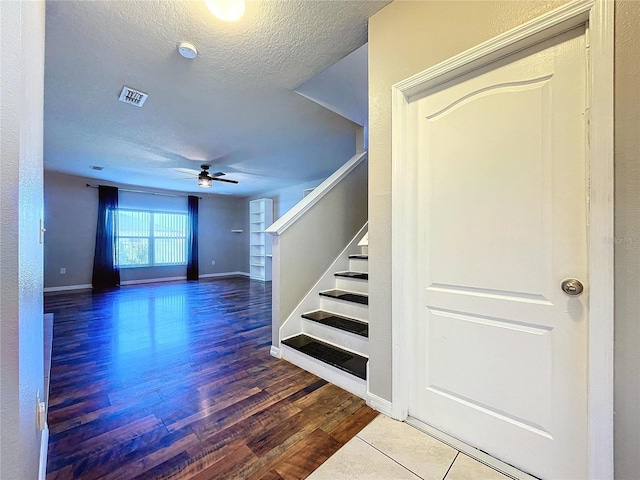 staircase featuring ceiling fan, hardwood / wood-style floors, and a textured ceiling