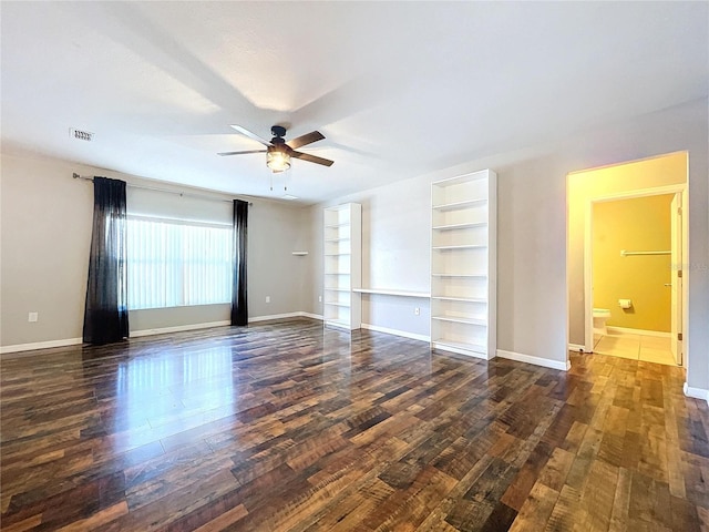 empty room featuring dark hardwood / wood-style flooring, built in features, and ceiling fan