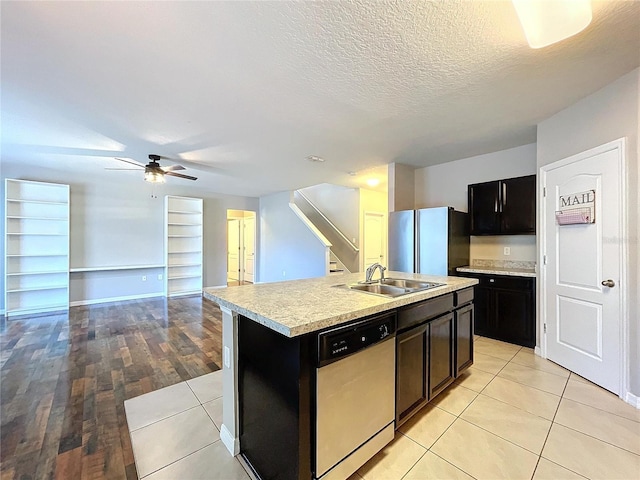 kitchen featuring appliances with stainless steel finishes, a textured ceiling, ceiling fan, sink, and a center island with sink