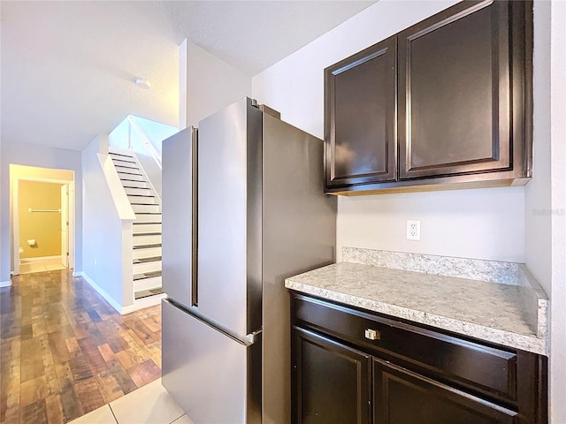 kitchen with stainless steel fridge, dark brown cabinetry, and light hardwood / wood-style floors