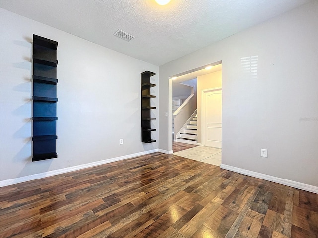 unfurnished room with hardwood / wood-style floors and a textured ceiling