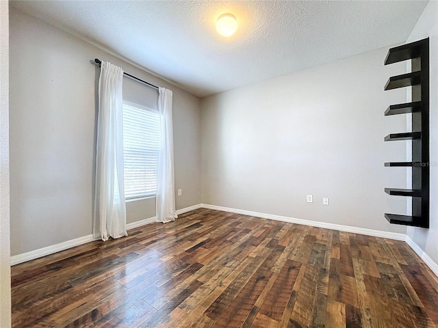 unfurnished room featuring a textured ceiling and dark hardwood / wood-style flooring