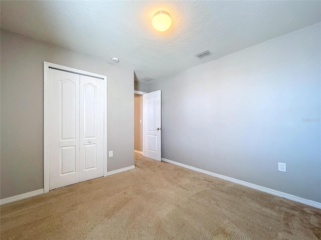 unfurnished bedroom featuring carpet, a textured ceiling, and a closet