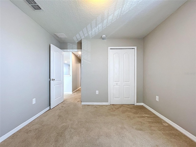 unfurnished bedroom with light carpet, a closet, and a textured ceiling