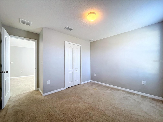 unfurnished bedroom with carpet, a textured ceiling, and a closet