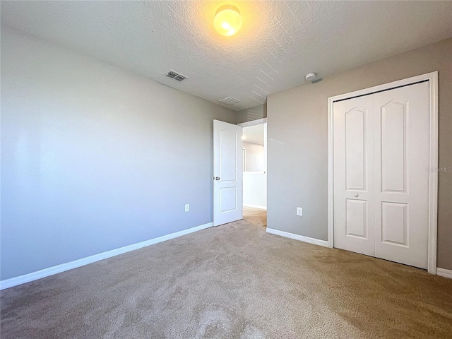 unfurnished bedroom with carpet flooring, a textured ceiling, and a closet